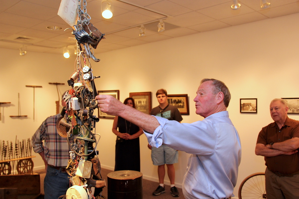 A man touches an art installation made of hardware in Taber Art Gallery